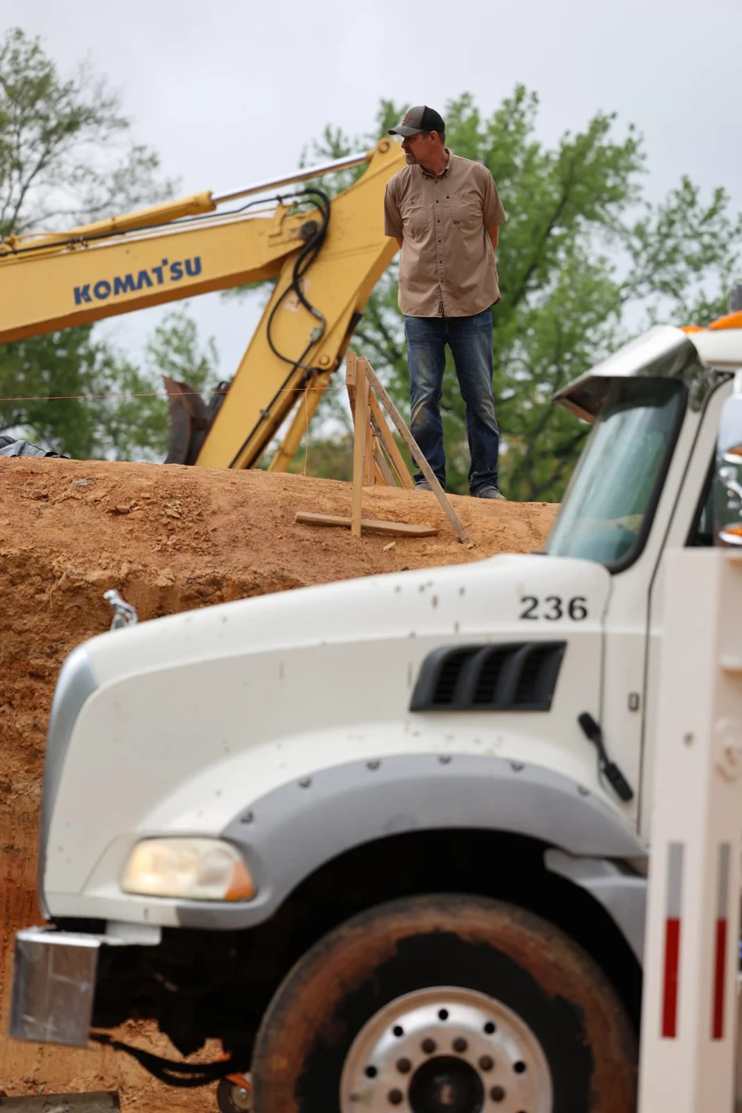 Bryan working at a construction site beside an excavator and truck